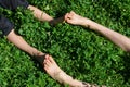 Small feet meeting bigger feet, feet contact of two kids sitting on the grass on a sunny bright day - concept of happy childhood, Royalty Free Stock Photo