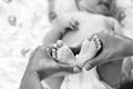 Small feet of a newborn baby in mother`s hands, mother holds the baby`s heels in the shape of a heart, black and white frame Royalty Free Stock Photo