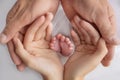 Small feet of a newborn in the hands of parents. Loving palms of the hands of mother and father. Royalty Free Stock Photo