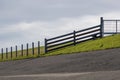 a small fence on top of a hill near a bench