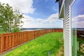 Small fenced backyard of a large blue house. With grass filled garden. Royalty Free Stock Photo