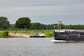 Small ferry crossing Dutch river Meuse waiting for cargo ship