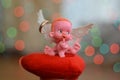 A small figure of an angel sitting on or near a jewelry box close up, a background bokeh of twinkling party lights