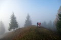 Small figure of lonely hikers enjoying his time on wild forest trail on foggy autumn day