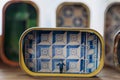 Small figure of tram conductor in colorful tin of canned sardines near azulejo tiles wall. Artwork in souvenir store