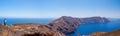 Small figure of woman on hiking trail on Santorini island. Panorama Santorini view. Hiking on the island.