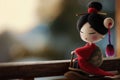 A small figurine of a geisha doll stands against a blurred traditional Japanese background, evoking the elegance and Royalty Free Stock Photo