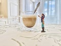 A small figurine of a girl washes a large glass mug of coffee Royalty Free Stock Photo