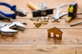 Small figurine of a house on the background of construction tools on a wooden table. House construction and renovation concept. Royalty Free Stock Photo