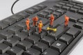 Small figurines of workers repairing computer keyboard Royalty Free Stock Photo
