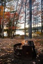 Small fire pit on a campsite by the lake in Fall with colourful foliage Royalty Free Stock Photo