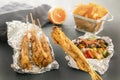 Small fish on skewers baked in foil, grilled vegetables, french fries and lemon on a wooden table. Royalty Free Stock Photo