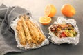 Small fish on skewers baked in foil, grilled vegetables and lemon on table Royalty Free Stock Photo