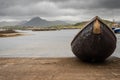 Small fishing boat ashore. Diamond hill mountain peak in clouds in the background. Harbour Derryherbert county Galway, Connemara, Royalty Free Stock Photo