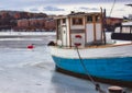 Fishing boat with a blue hull moored on a frozen river in winter