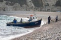 Small fishing boat landing on shingle beach at Beer, Devon, UK