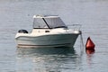 Small fishing boat with modern solar panel on top and inox rail in front tied to large red buoy in local harbor Royalty Free Stock Photo