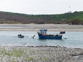 A small fishing boat moored in shallow water. One man in a rowing boat. Seaside landscape Royalty Free Stock Photo