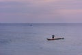 Small fishing boat with one fisherman throwing out his net on the sea near Puducherry in South India during sunrise