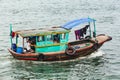 Small fishing boat over emerald water with towering limestone islands in the background in summer at Quang Ninh, Vietnam