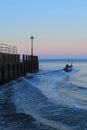 Small fishing boat passing wooden groyne