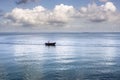 Small fishing boat in the sea with a fisherman inside against blue sky and big clouds Royalty Free Stock Photo