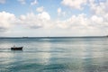 Small fishing boat in the sea with a fisherman inside against blue sky and big clouds Royalty Free Stock Photo