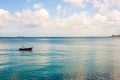 Small fishing boat in the sea with a fisherman inside against blue sky and big clouds Royalty Free Stock Photo