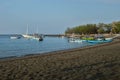 Small fishing boats on black beach.