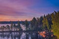 Small fishing or pleasure boat boat moored on Paijanne lake. Beautiful sunrise scape with stone beach, pine forest and water. Lake