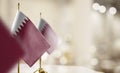 Small flags of the Qatar on an abstract blurry background