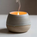 A small flame flickers inside a ceramic candle holder with a smooth, rounded design. The holder is Royalty Free Stock Photo