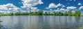 Small flat lake against the sky with clouds. Trees on the shore of the reservoir. Summer holidays, fishing