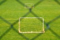 Small football field with two small goals outdoors on green grass behind fence