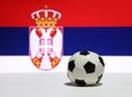 Small football on the white floor with white blue and red color, out focus eagle and crown picture of Serbian nation flag.