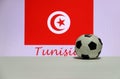 Small football on the white floor and Tunisian nation flag with the text of Tunisia background. Royalty Free Stock Photo