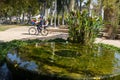 A small fountain in a pond in a public garden near the Florentin district, overgrown with algae and greenery. A father is carrying