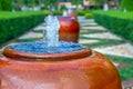 Small fountain water in red big clay jar in home or house garden.