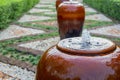 Small fountain water in red big clay jar in public park garden. Royalty Free Stock Photo