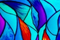 Small fragment of a beautiful colorful stained glass background including orange, turquoise, blue, and violet pieces.