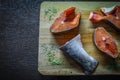 Small fresh pieces of red fish pink salmon lie on a wooden cutting Board with dried herbs and seasonings Royalty Free Stock Photo