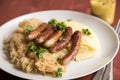 Small fried Bavarian German NÃÂ¼rnberger sausages with sauerkraut, mashed potatoes and mustard on wooden table background