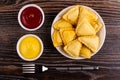 Fried savory pies in plate, bowls with ketchup and mayonnaise, fork on wooden table. Top view Royalty Free Stock Photo