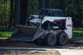 A small front loader clears the ground after construction work