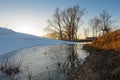 A small frozen pond in a ravine in the spring evening