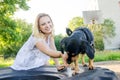 A small funny dog is looking for a treat that a beautiful blonde girl in a light dress gives her Royalty Free Stock Photo