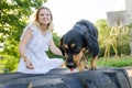 A small funny dog is looking for a treat that a beautiful blonde young woman in a light dress gives her