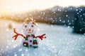 Small funny toy baby snowman in knitted hat and scarf in deep snow outdoor on blurred mountains landscape and falling big Royalty Free Stock Photo