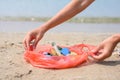 Small garbage collected on the beach left by tourists. The girl holds a package with garbage on the background of the sea. Royalty Free Stock Photo