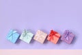 Small gift boxes of different colors with ribbons lies on a violet and pink color background Royalty Free Stock Photo